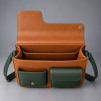 Open tan and green leather messenger bag showing roomy compartments and front pockets