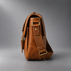 Side view of tan leather camera shoulder bag showing structured profile and strap attachment